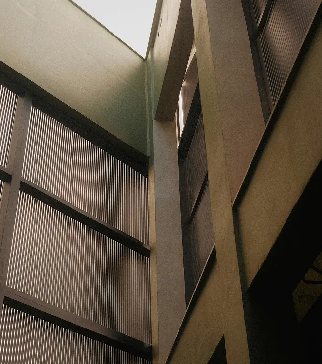View looking upward inside a modern building with tall vertical windows and geometric shapes.